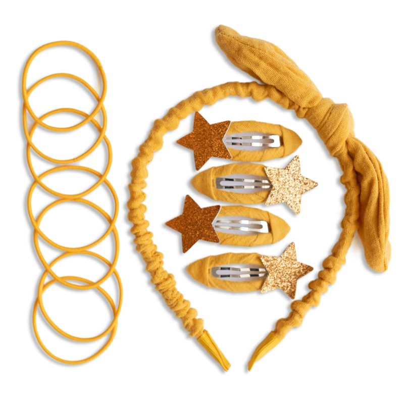 Gelbes Haarband neben Spiral-Haargummis und Haarspangen mit Glitzersternen auf weißem Hintergrund