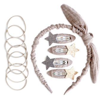 Flache Anordnung von Haarschmuck und Accessoires mit Haargummis auf der linken Seite und einem Haarband mit Knoten sowie Haarspangen mit Sternmotiv auf weißem Hintergrund