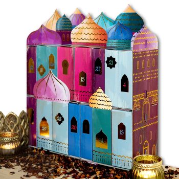 Bunt bemalter Adventskalender in Form einer orientalischen Palastfassade mit nummerierten Türchen und Teelicht im Vordergrund auf einer mit Blütenblättern bestreuten Oberfläche
